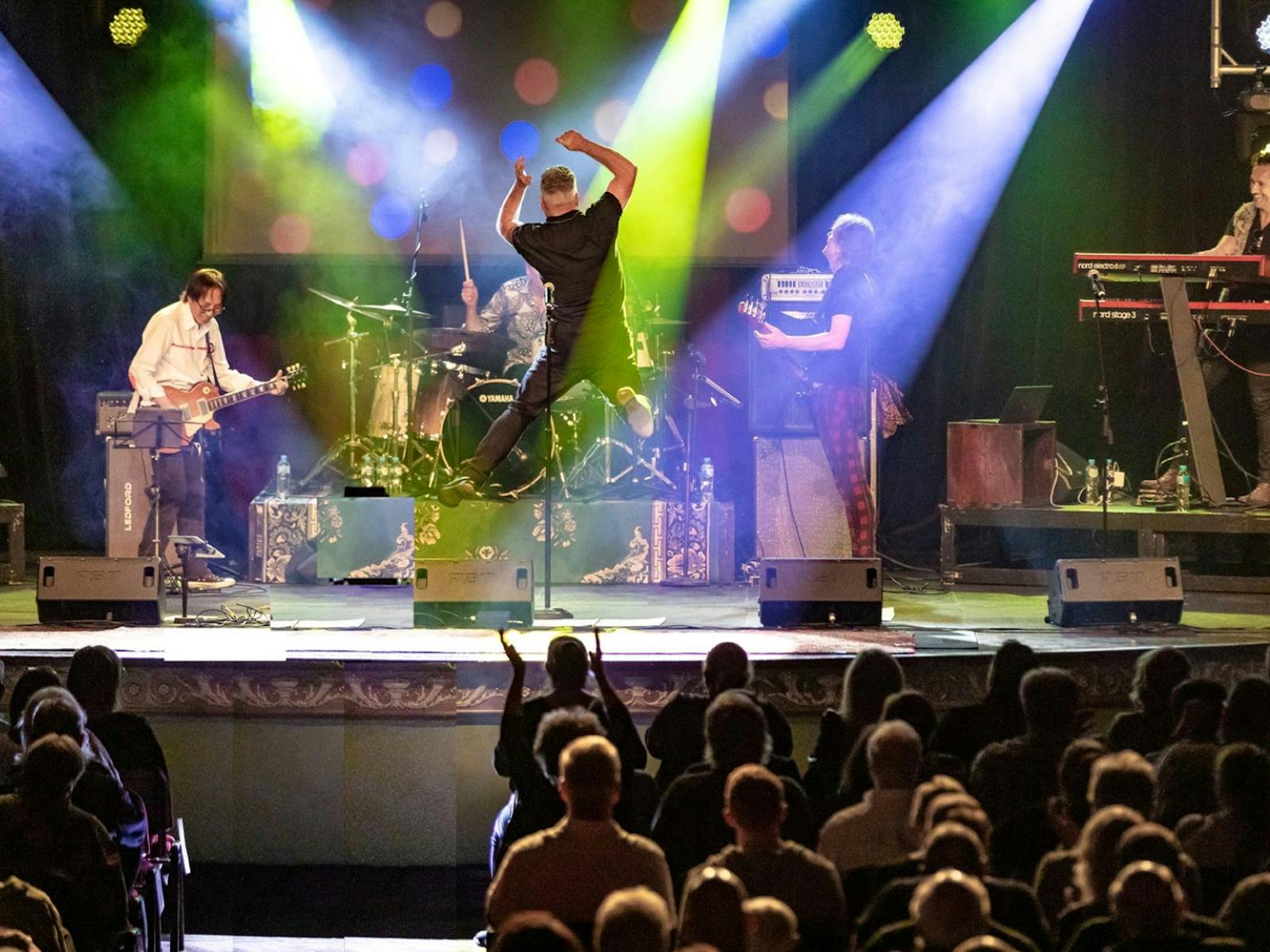 Bnd on stage with the singer leaping