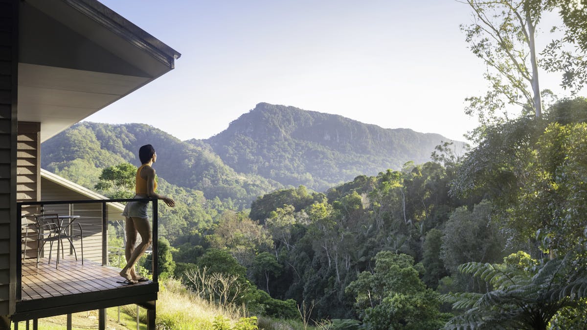 Woman standing on balcony looking out over view of Currumbin Valley