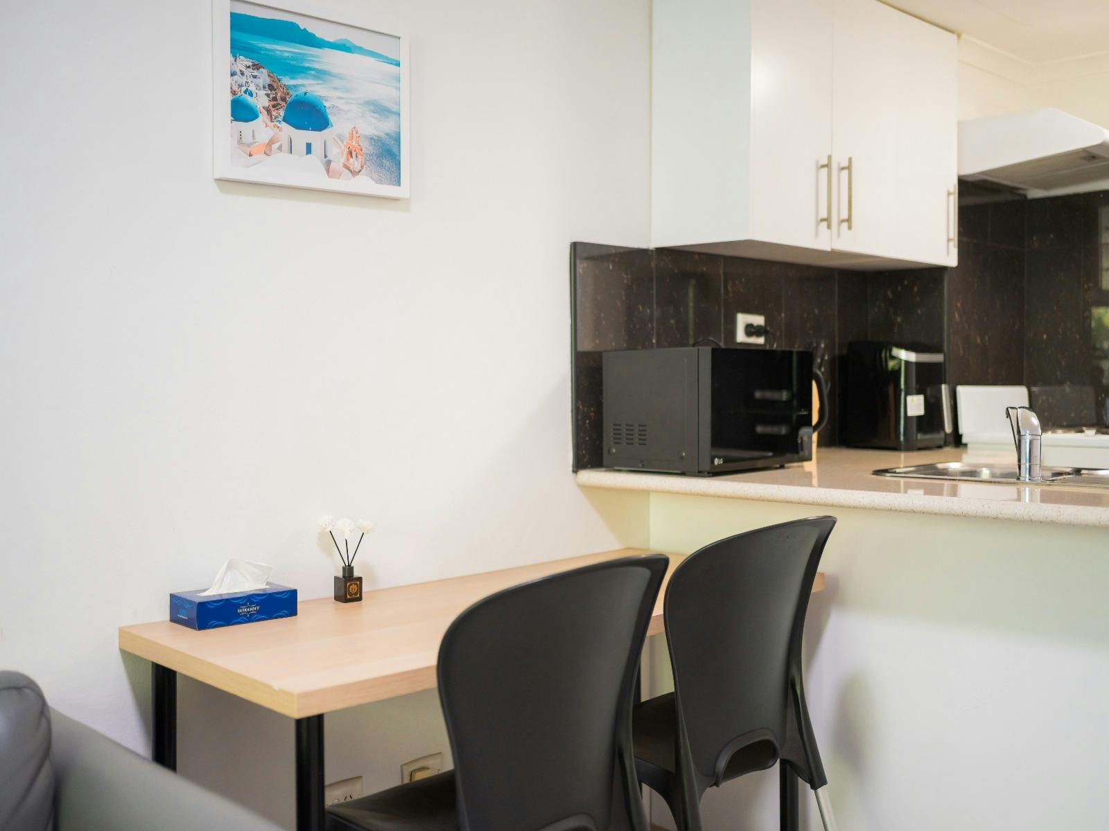 Open-plan kitchen and dining area with breakfast bar, seating for two and modern appliances.