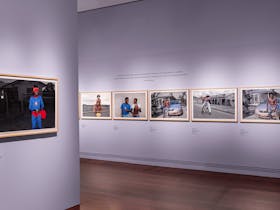 A photograph of an exhibition, framed pictures line white walls.