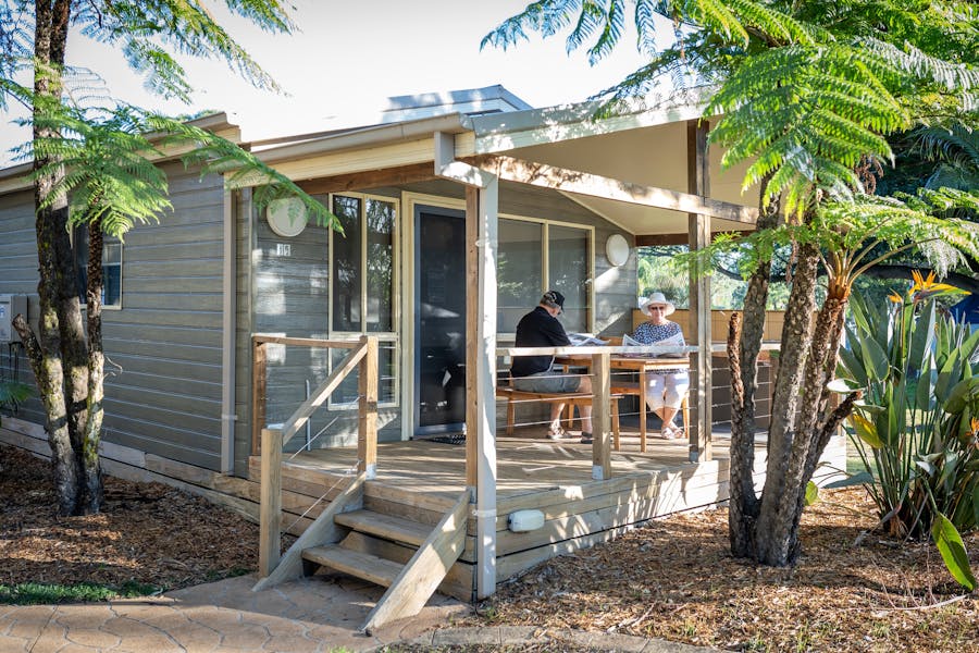 Couple on cabin deck at Seven Mile Beach Holiday Park