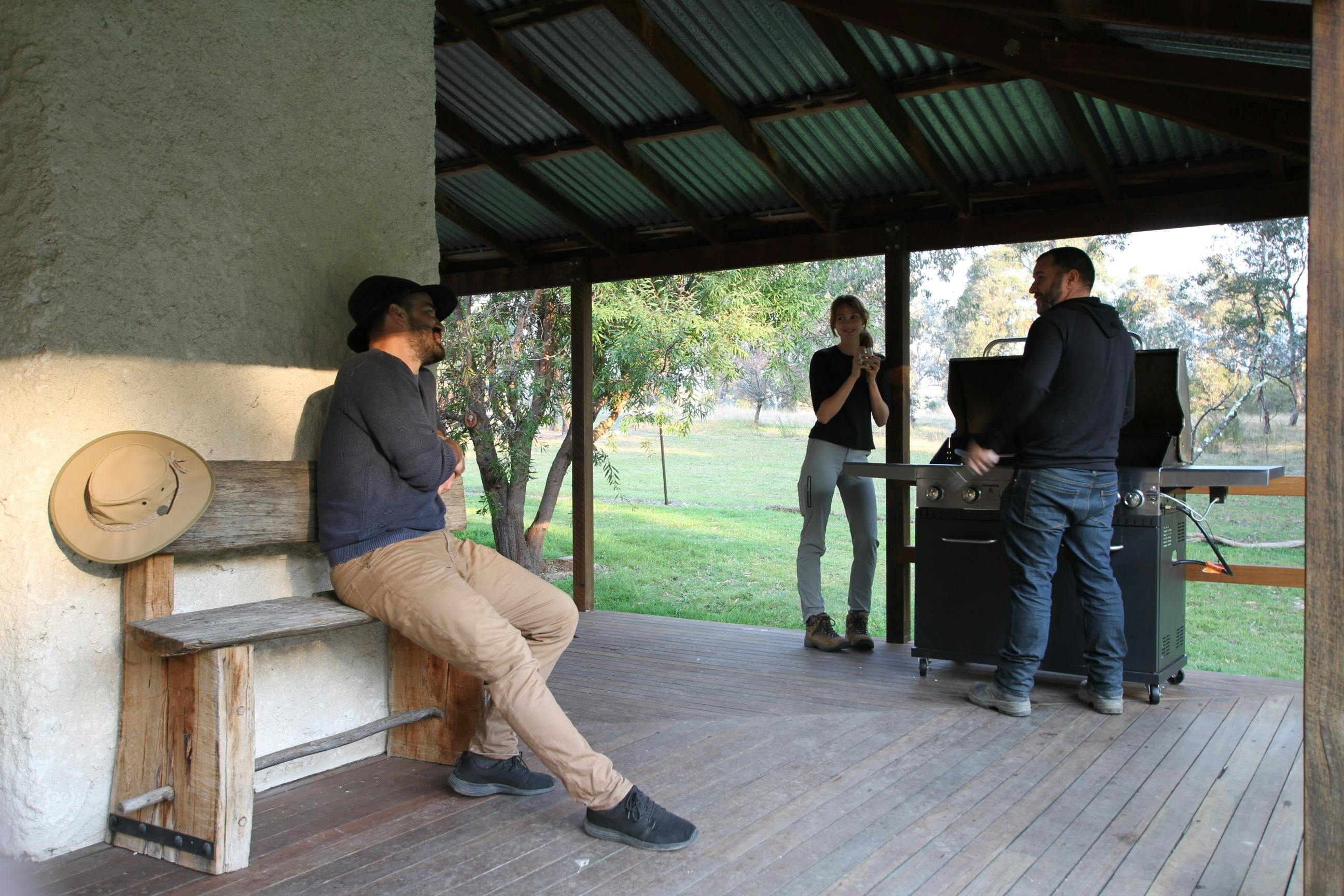 3 people having a BBQ on a verandah