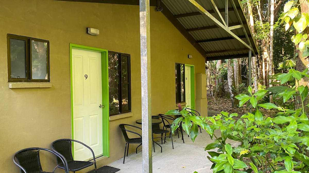 Covered concrete patio with Seats outside motel rooms with lime green framed doors