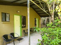 Covered concrete patio with Seats outside motel rooms with lime green framed doors
