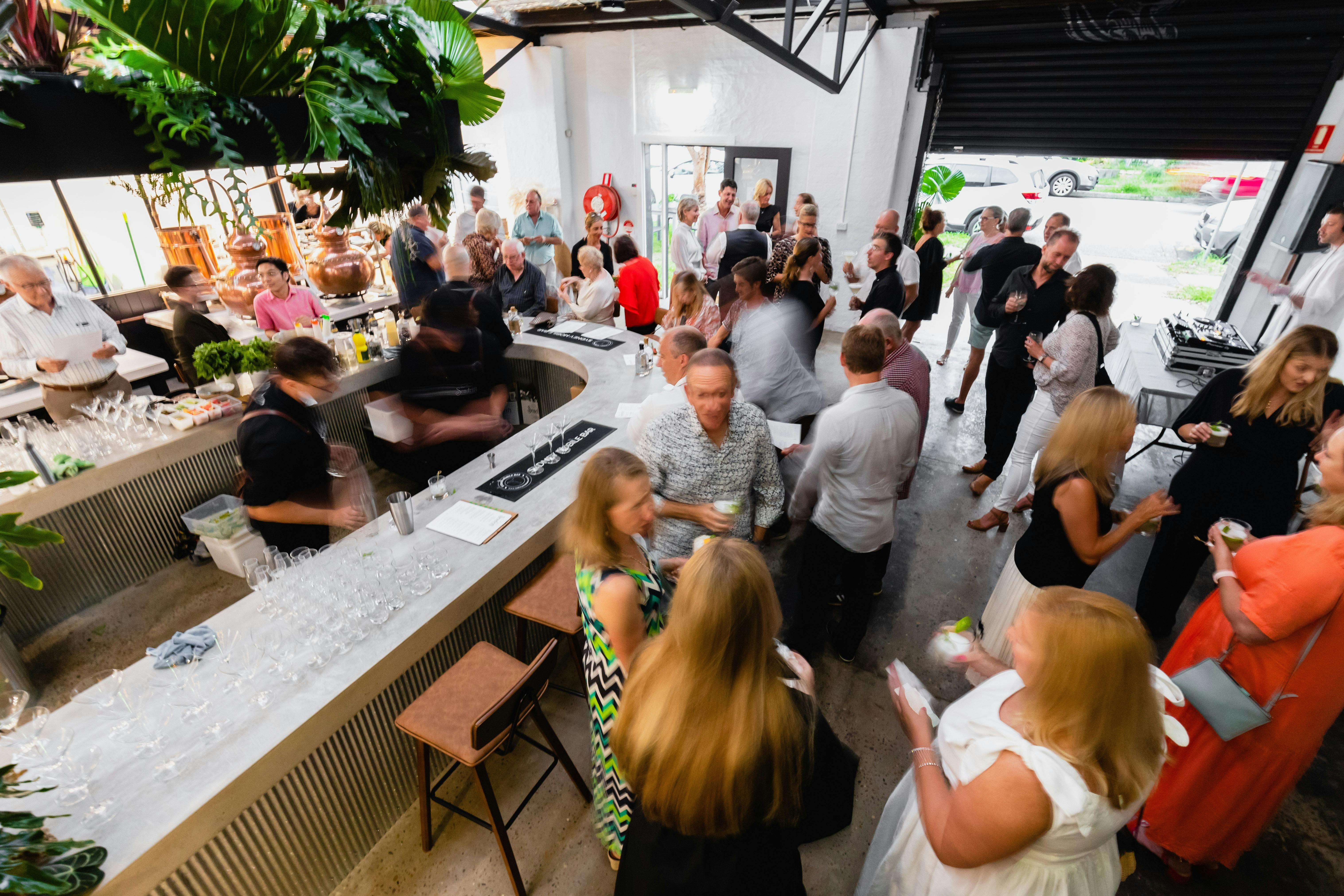 People in the distillery for an event, gathered around the bar talking.