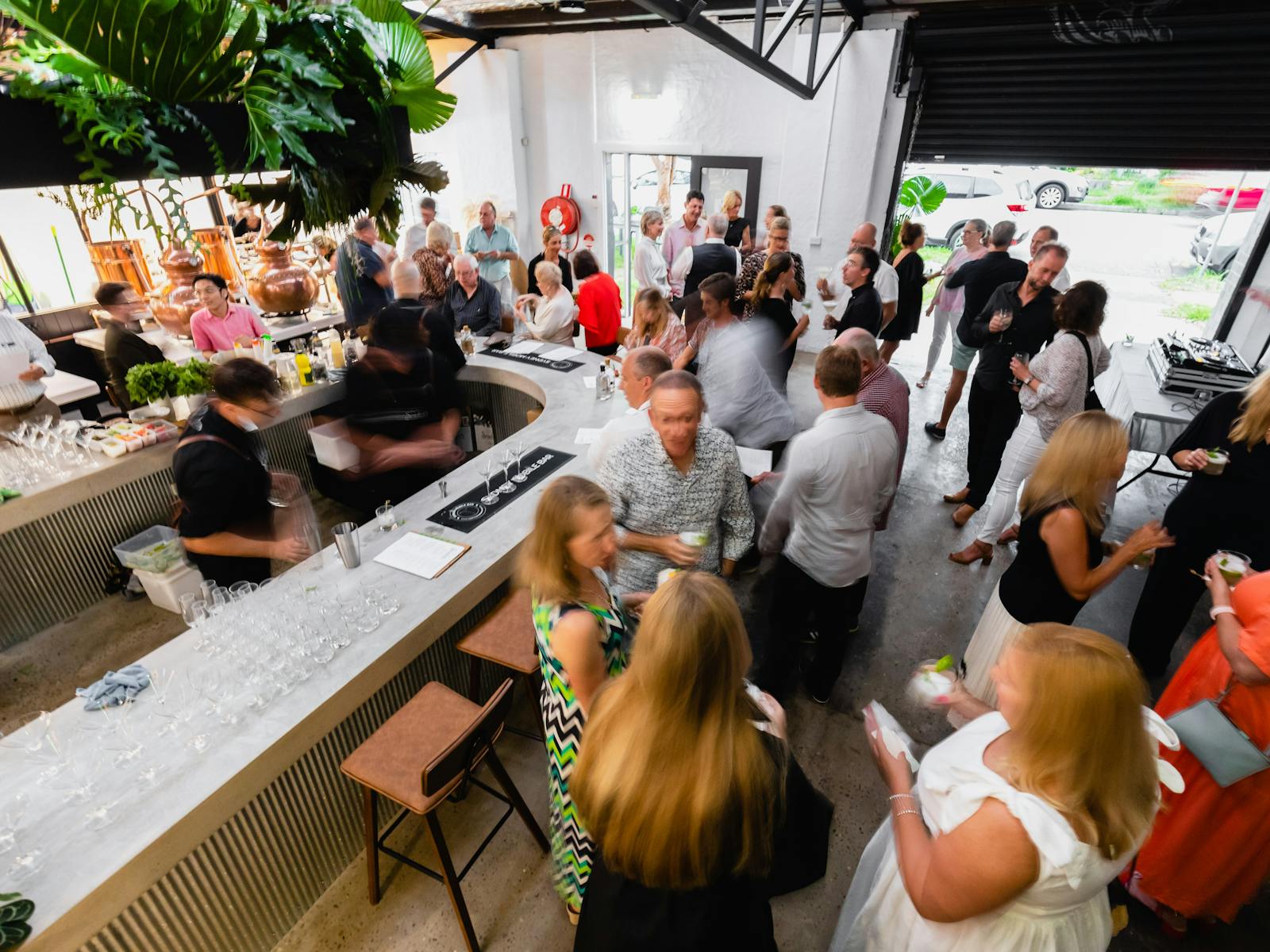 People in the distillery for an event, gathered around the bar talking.