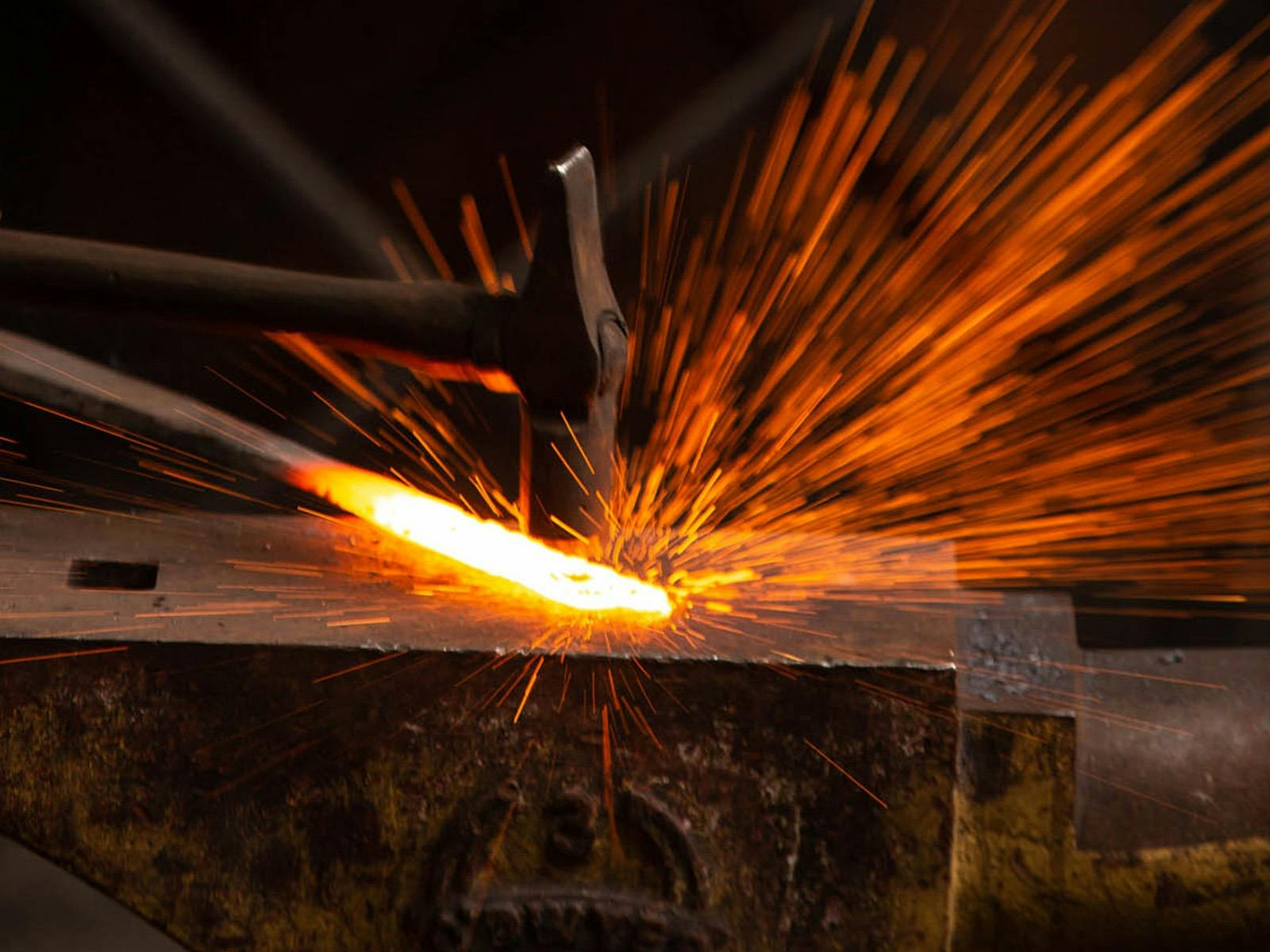 Hammer striking heated metal on anvil creating sparks. Hammer striking heated metal on anvil creating sparks.