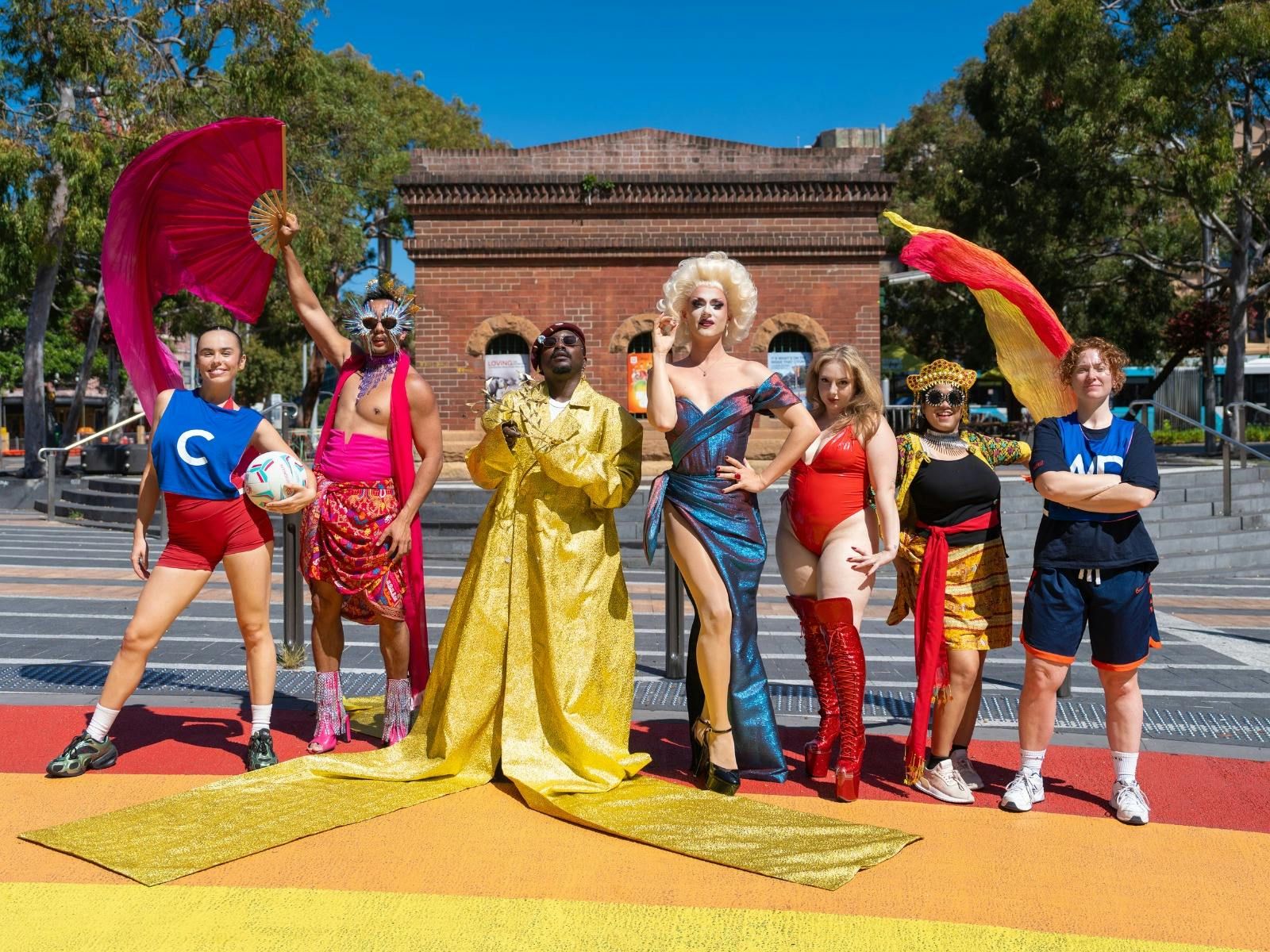 Pride Fest performers stand on a rainbow crossing in various poses.