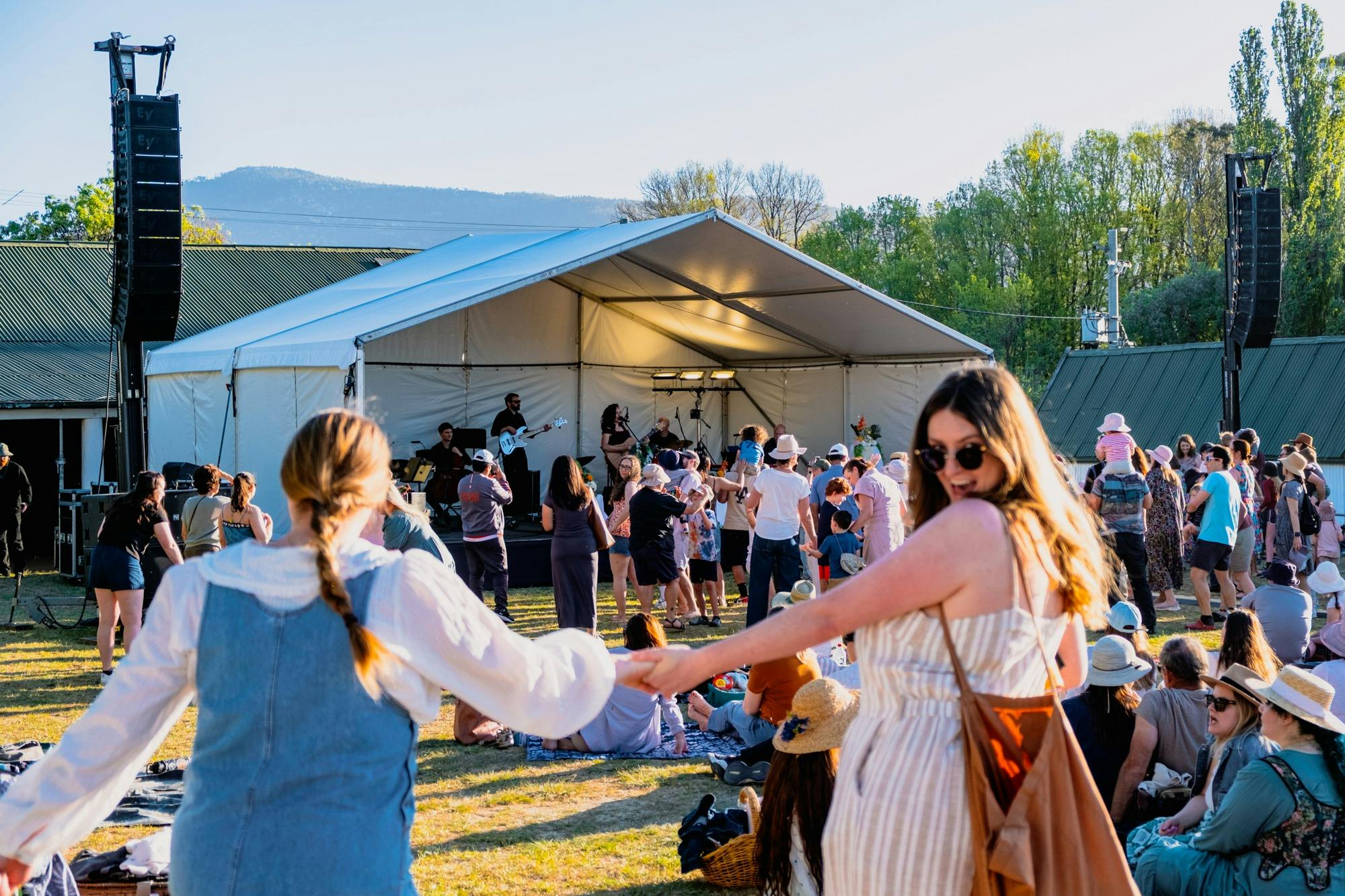 Two women running moving towards Live at Lanyon stage to dance, one looking back at camera