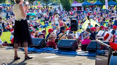 performer on stage with audience inb background at Carols in Town Park Canberra
