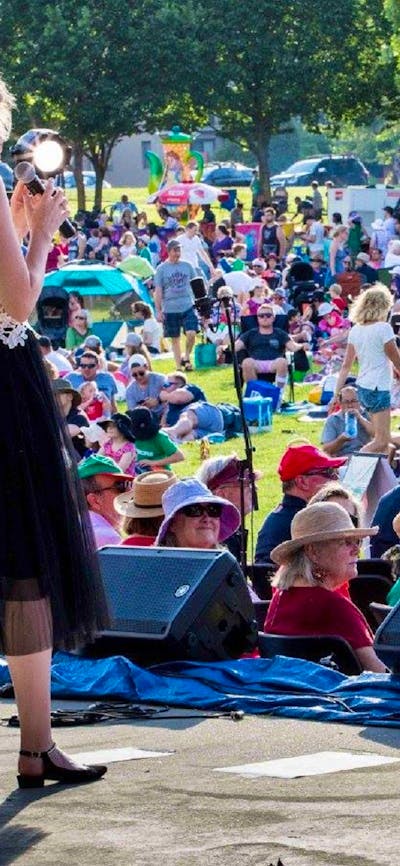 performer on stage with audience inb background at Carols in Town Park Canberra