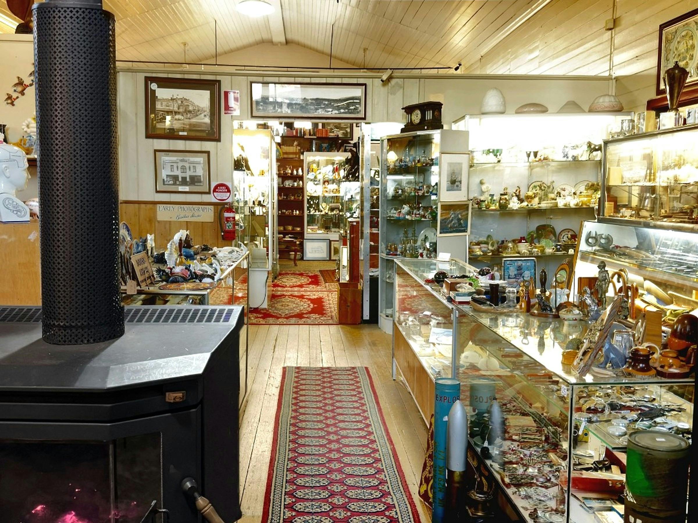 Antique shop interior with wood heater, red runner rug, and timber display cabinets