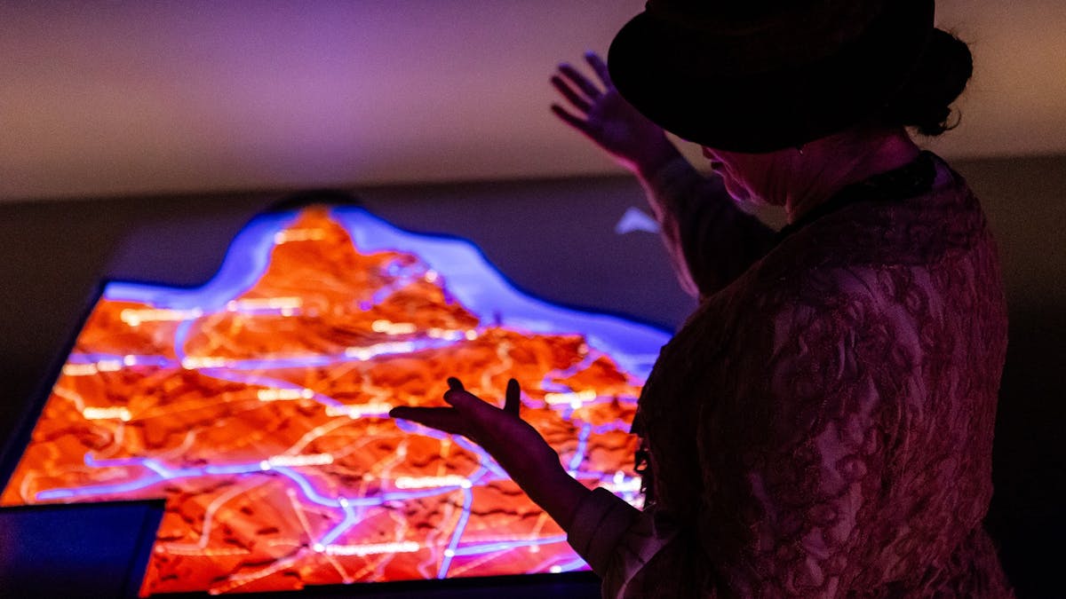 Museum visitor explored holographic Queensland map projection.