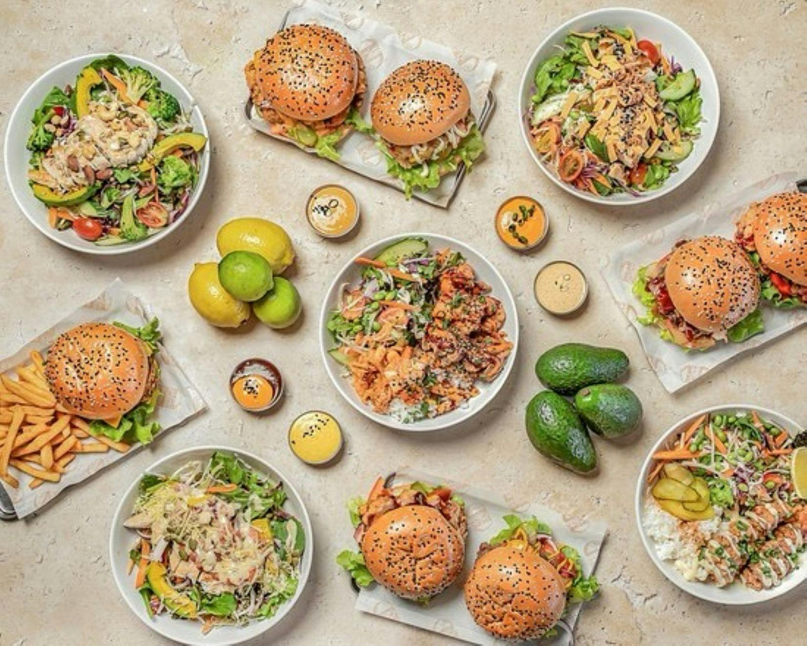 Tablescape of salad bowls, burgers, sauces and avocadoes