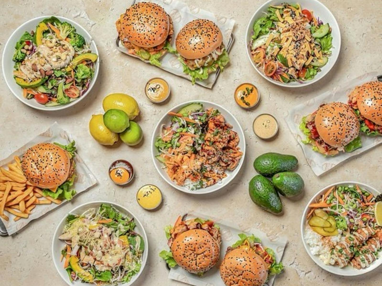 Tablescape of salad bowls, burgers, sauces and avocadoes