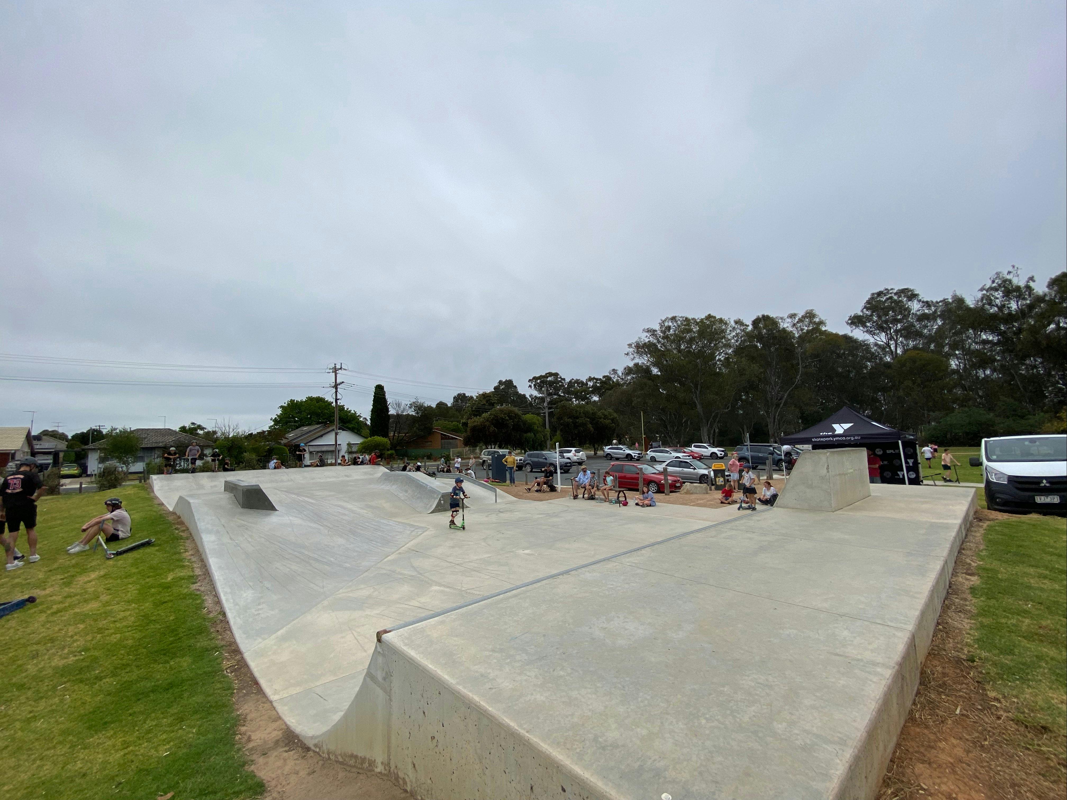 Concrete skate park grass people with scooters