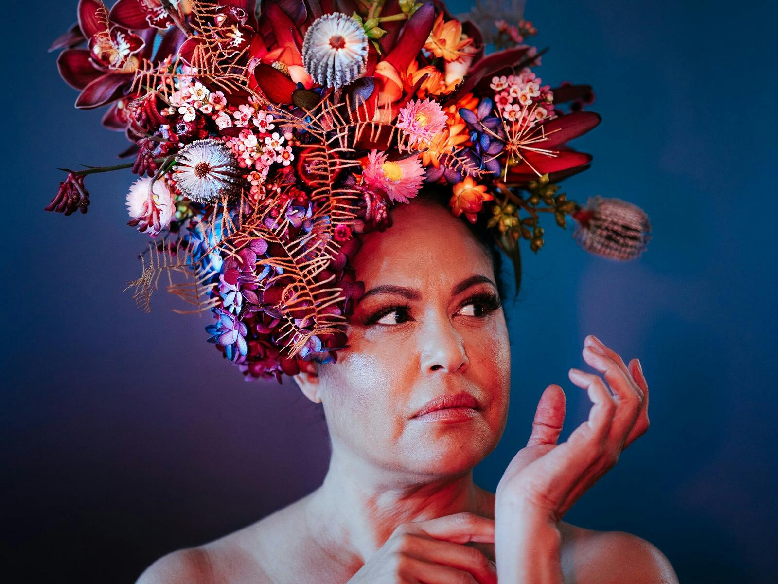 Woman with flower hat looking to her left with hand