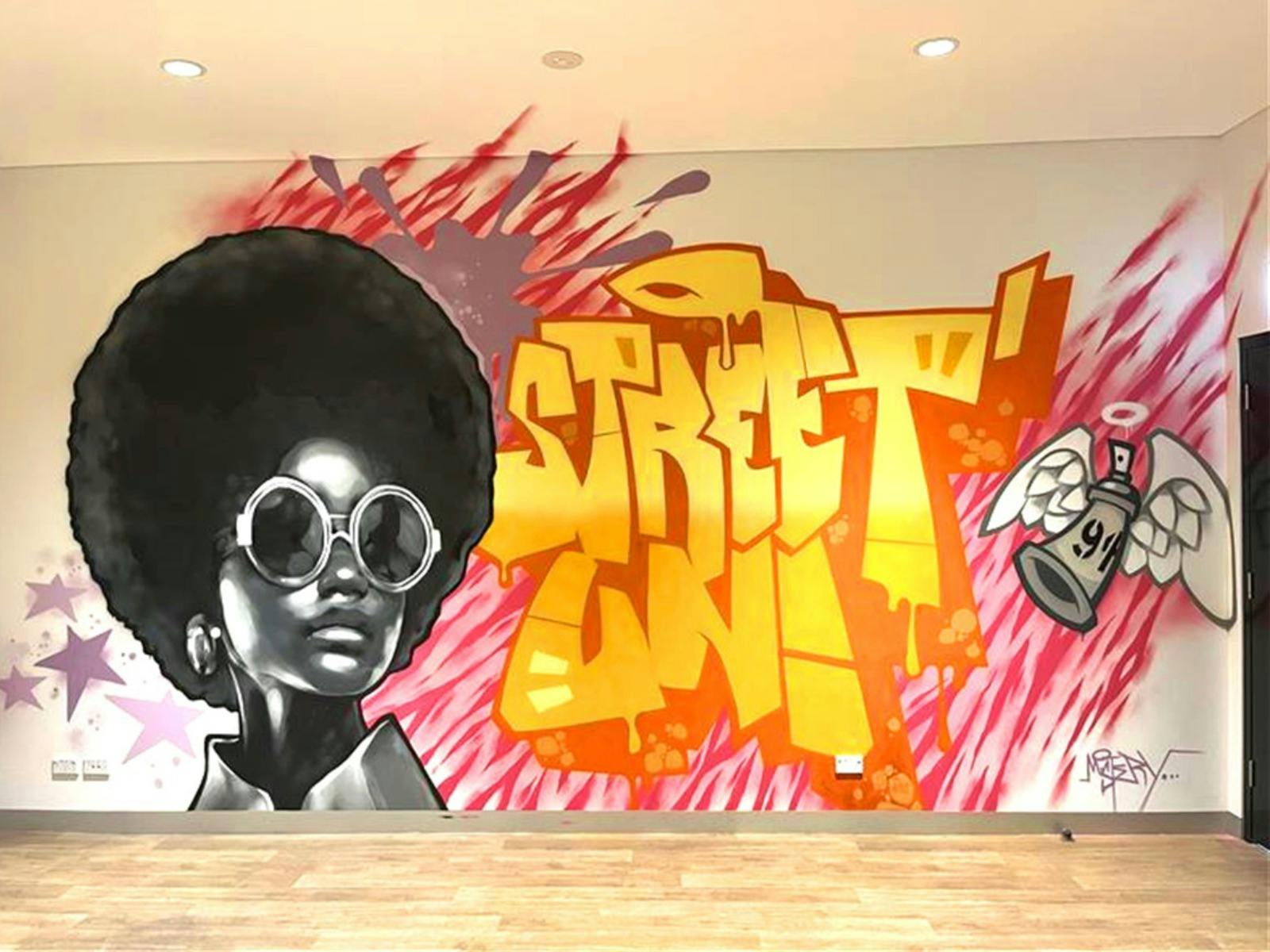 Mural artwork with a woman wearing sunglasses and pink and yellow lines in background.