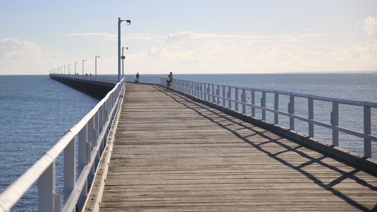 photo showing the wooden walkway on Urangan Pier stretching into the distance with people fishing