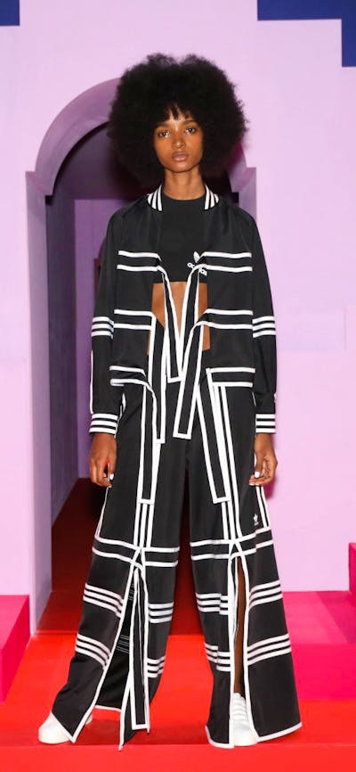 Lady modelling outfit behind pink stairs and purple background