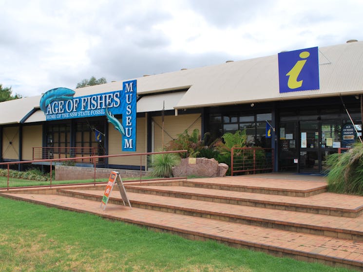 Front facade of the museum, green grass, steps and blue fish singage