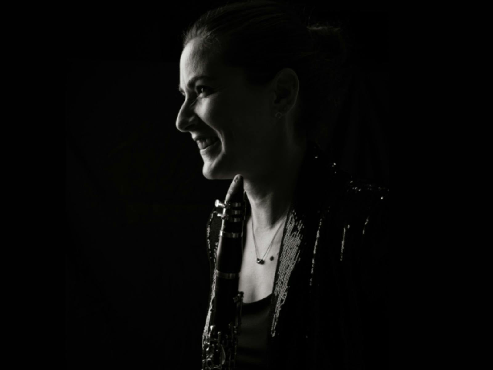 Black-and-white portrait of a clarinet player in profile, looking toward the light