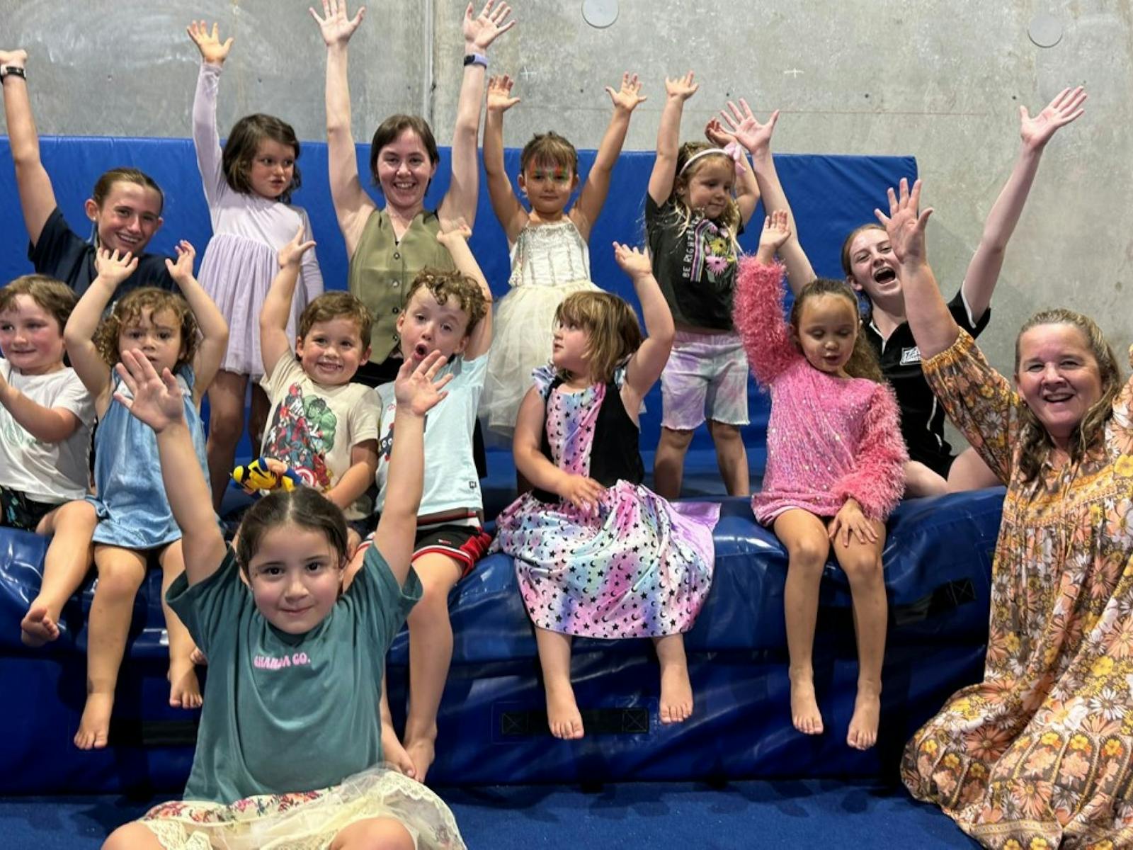 Multiple children smiling with their arms raised