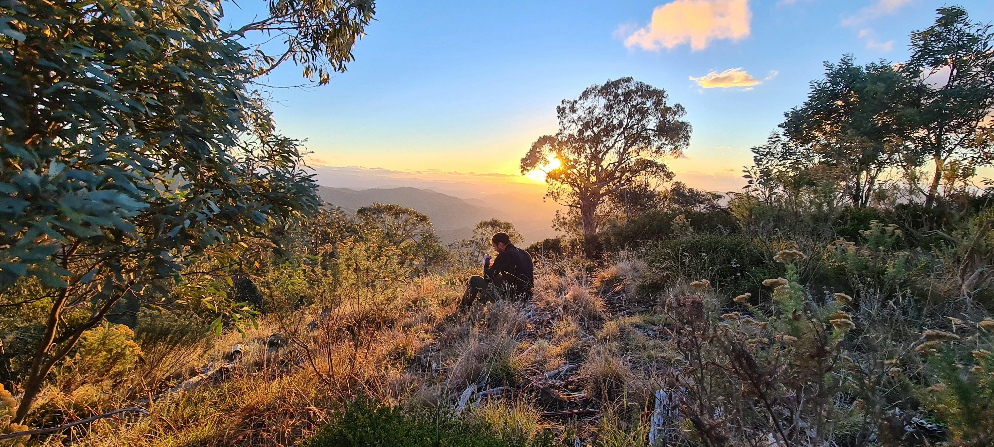 A hiker enjoying dinner while watching the sun set on another day.