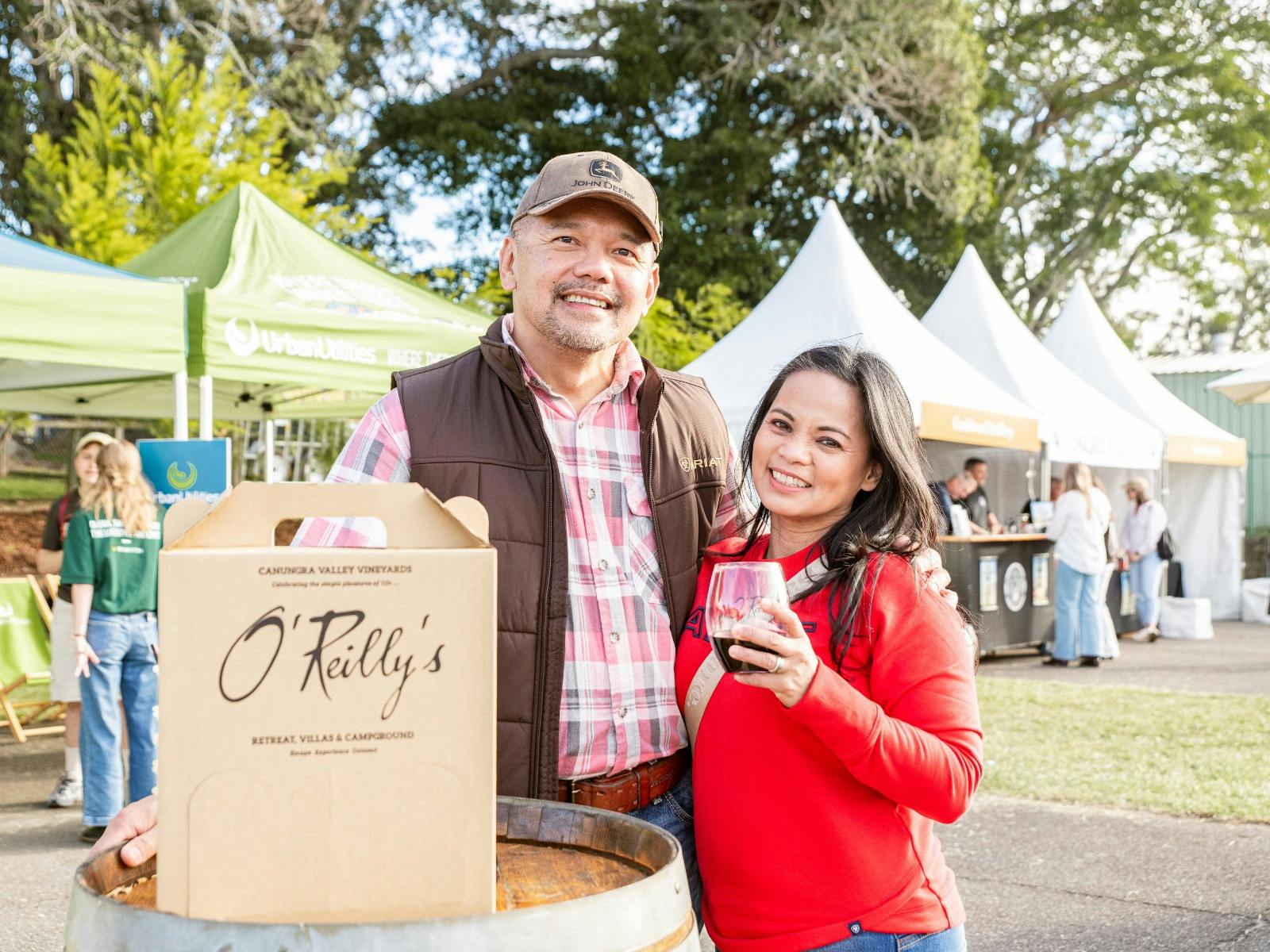 Man and women holding wine glass and smiling towards camera at Winter Harvest Festival