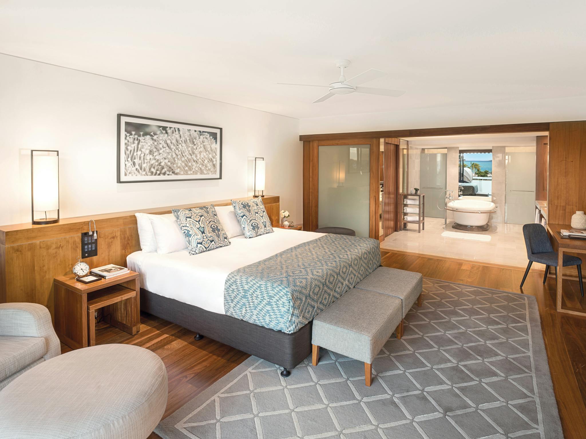 A luxurious suite with a king-sized bed, wooden furniture, and an open bathroom with a bathtub A luxurious suite with a king-sized bed, wooden furniture, and an open bathroom with a bathtub