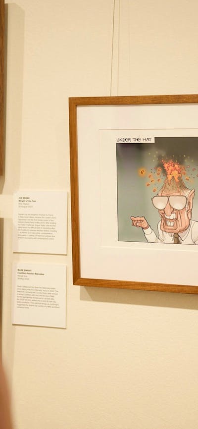 Woman views framer political cartoon in gallery.
