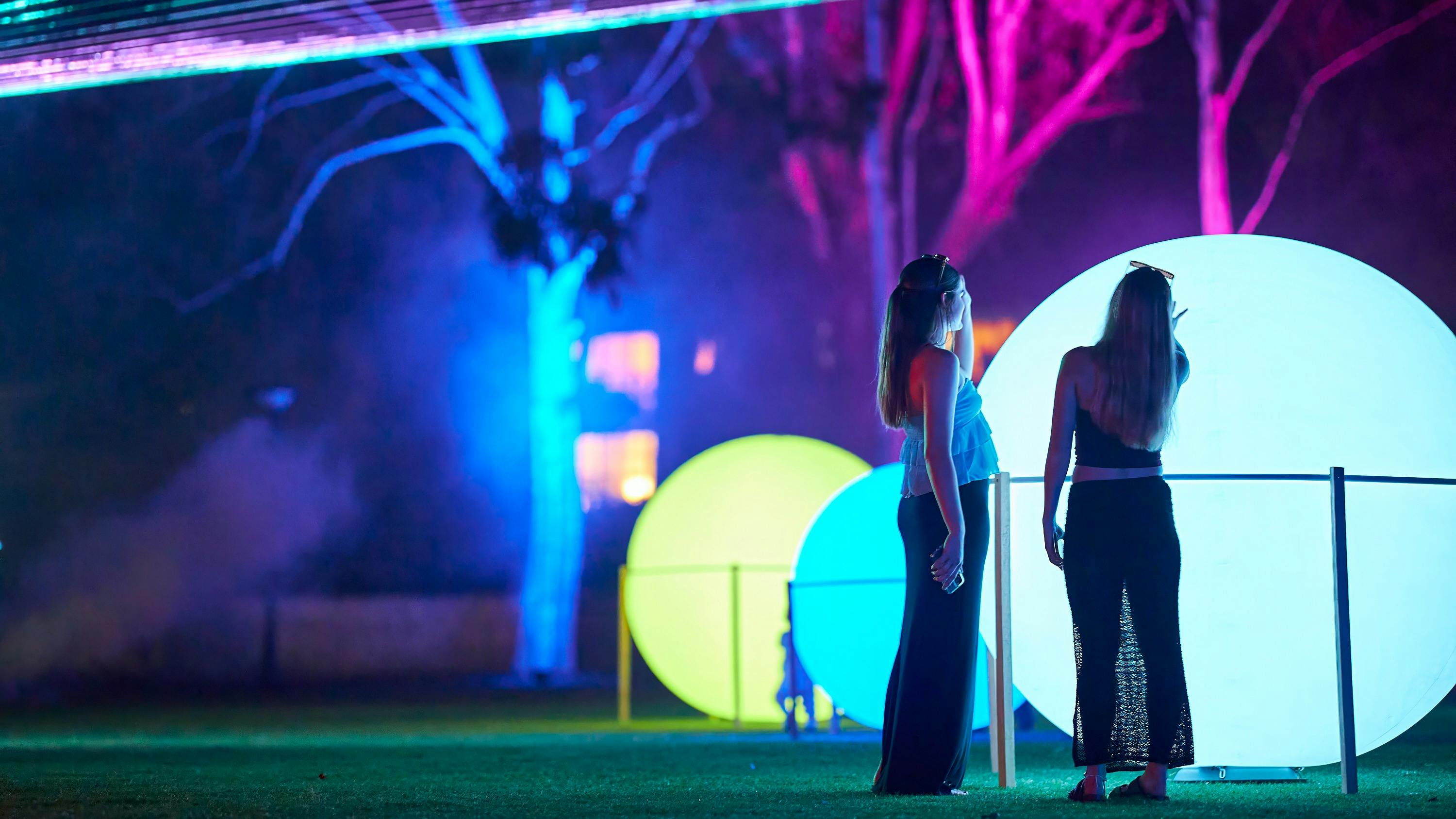Two women interact with touch reactive light spheres