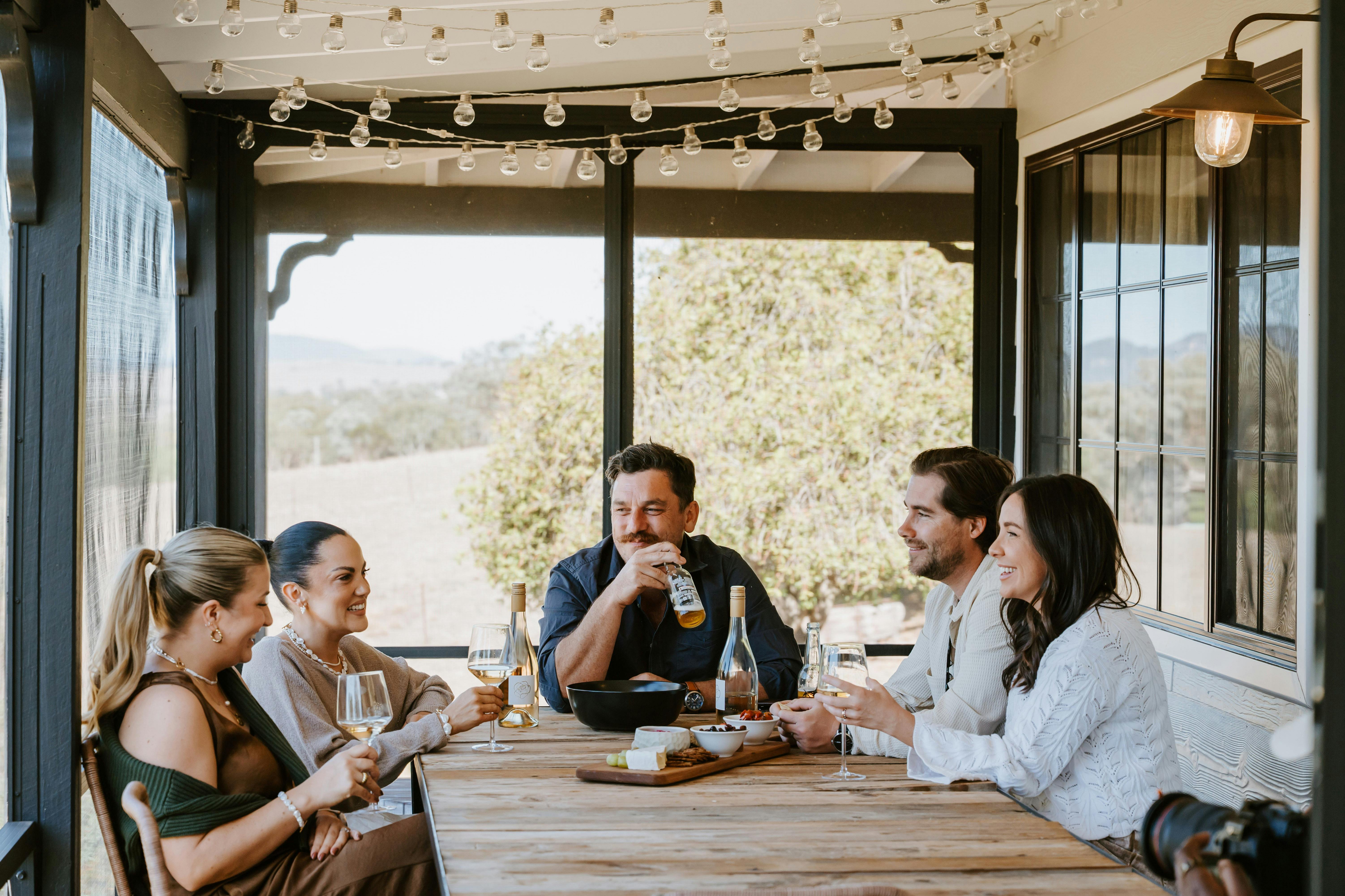 Group of adults enjoying a wine and cheese board on the verandah