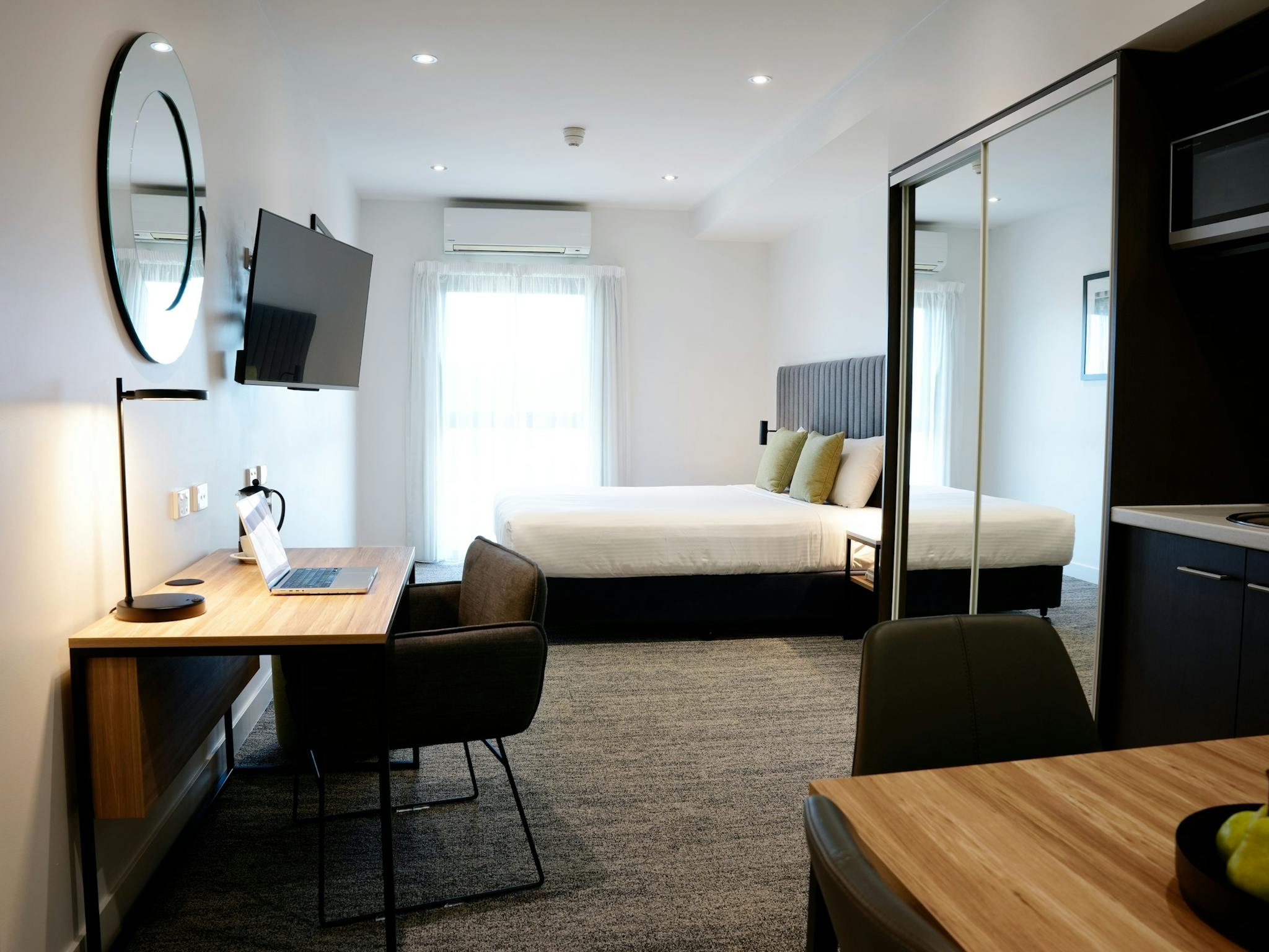 A shot of the Studio Apartment: a king bed, kitchenette, desk and dining table, with bathroom