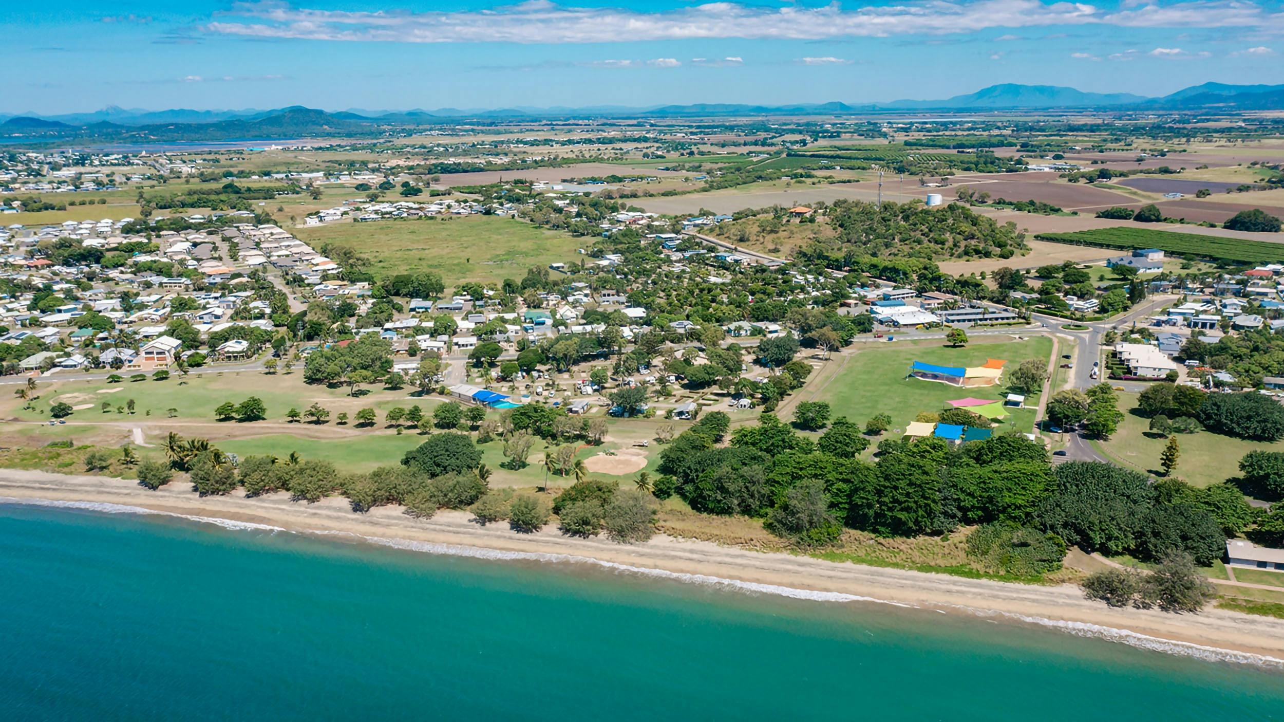 Aerial view of the coastal town of Bowen featuring a beach in the foreground.