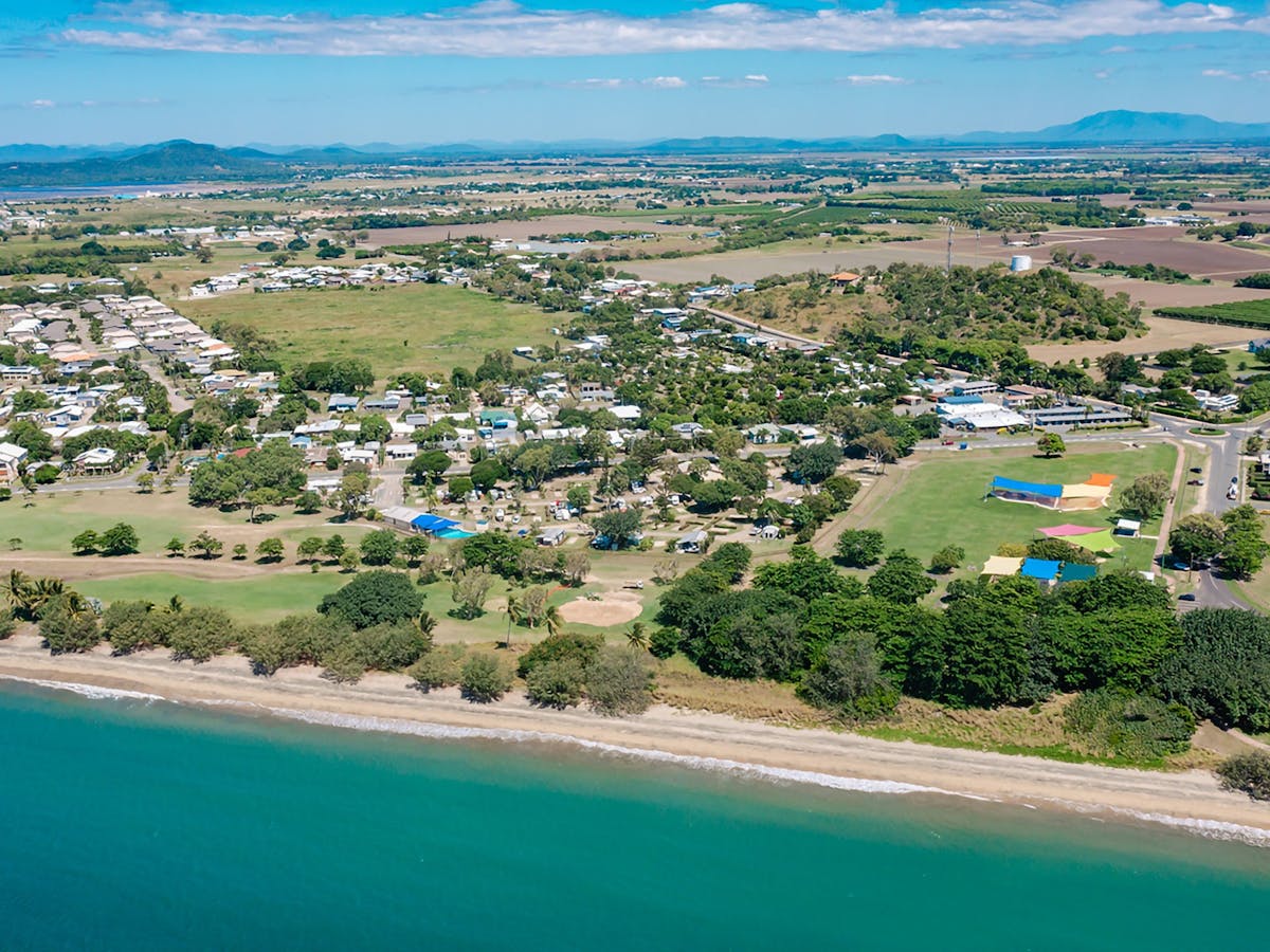 Aerial view of the coastal town of Bowen featuring a beach in the foreground.