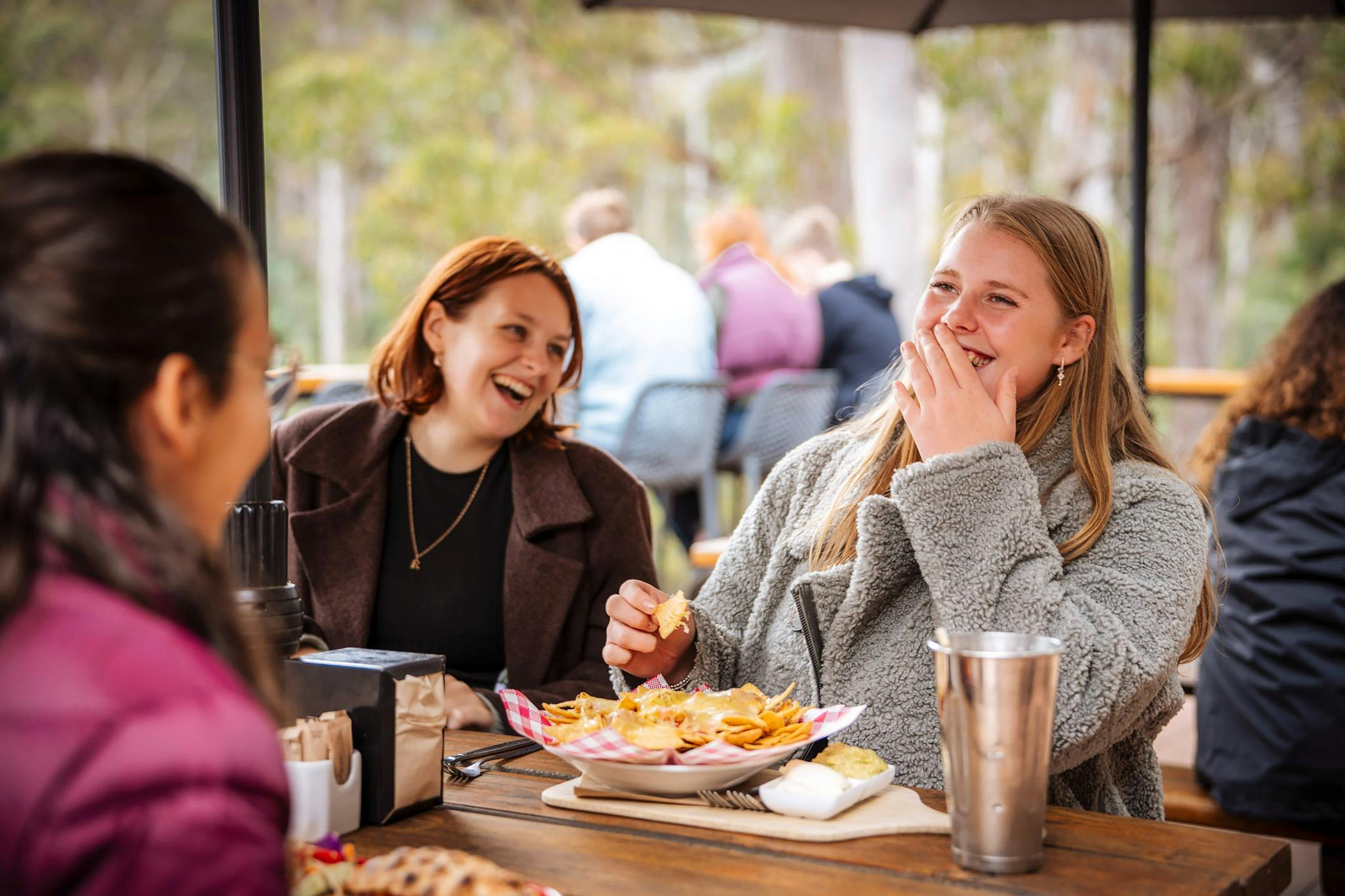 Two girls laughing while eating nachos on the deck at the Tahune Cafe