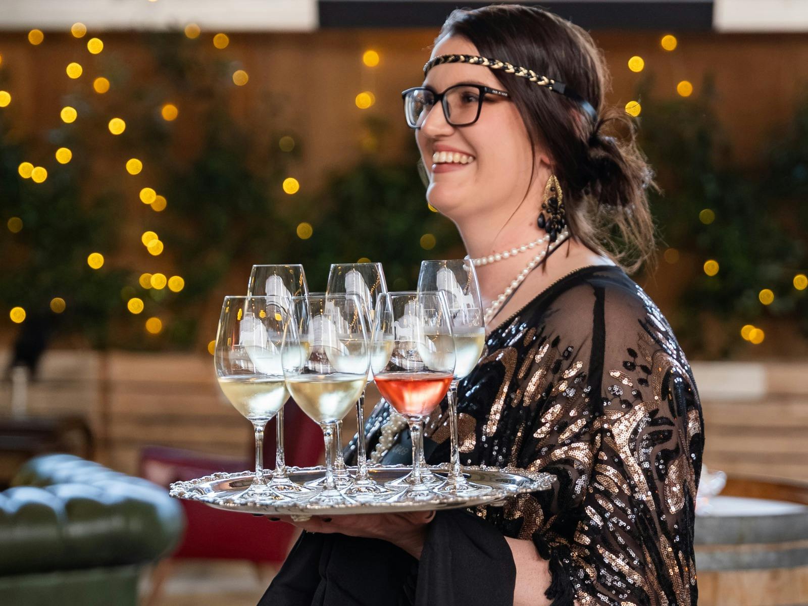 1920s themed server carrying a tray of wine
