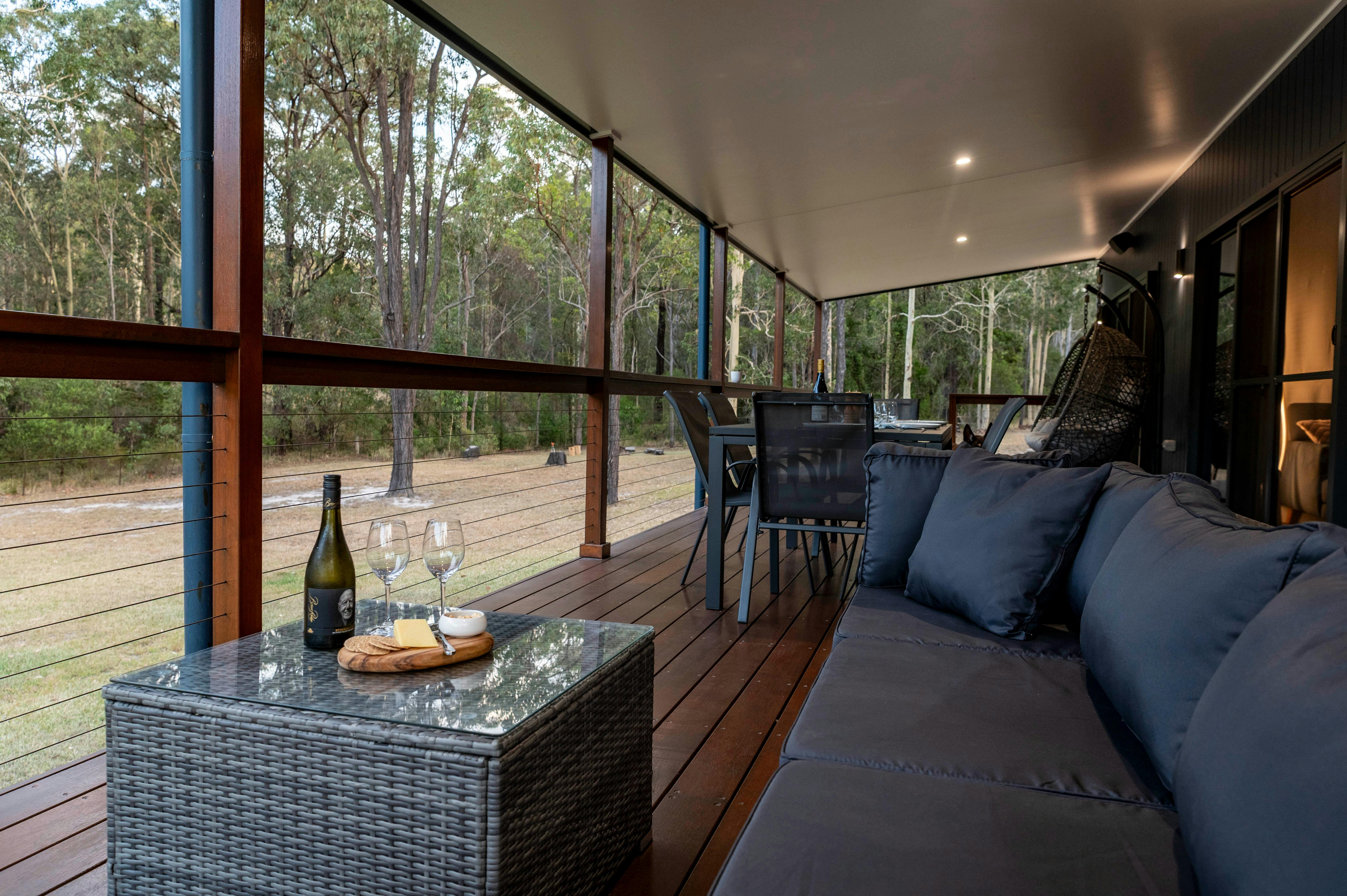 Covered deck with outdoor lounge and bush views at Mawarra Retreat