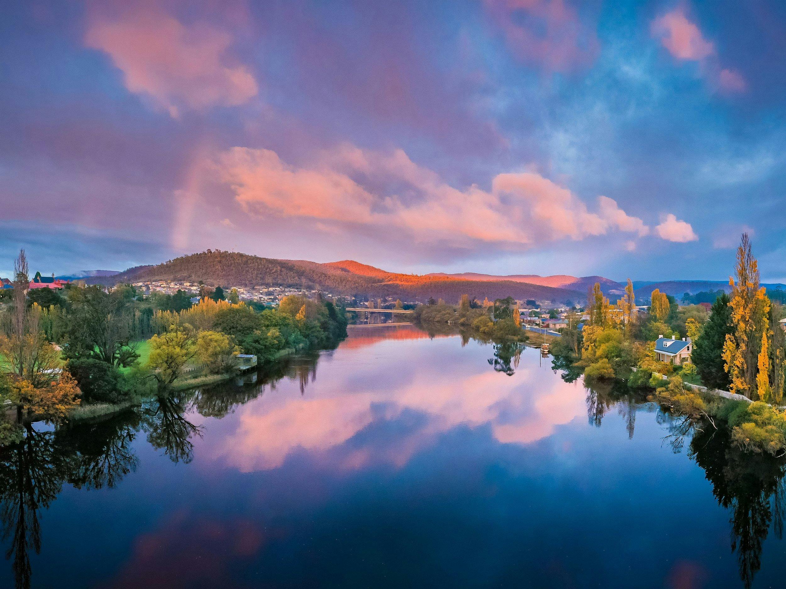 A still, calm river reflecting purples and blues.