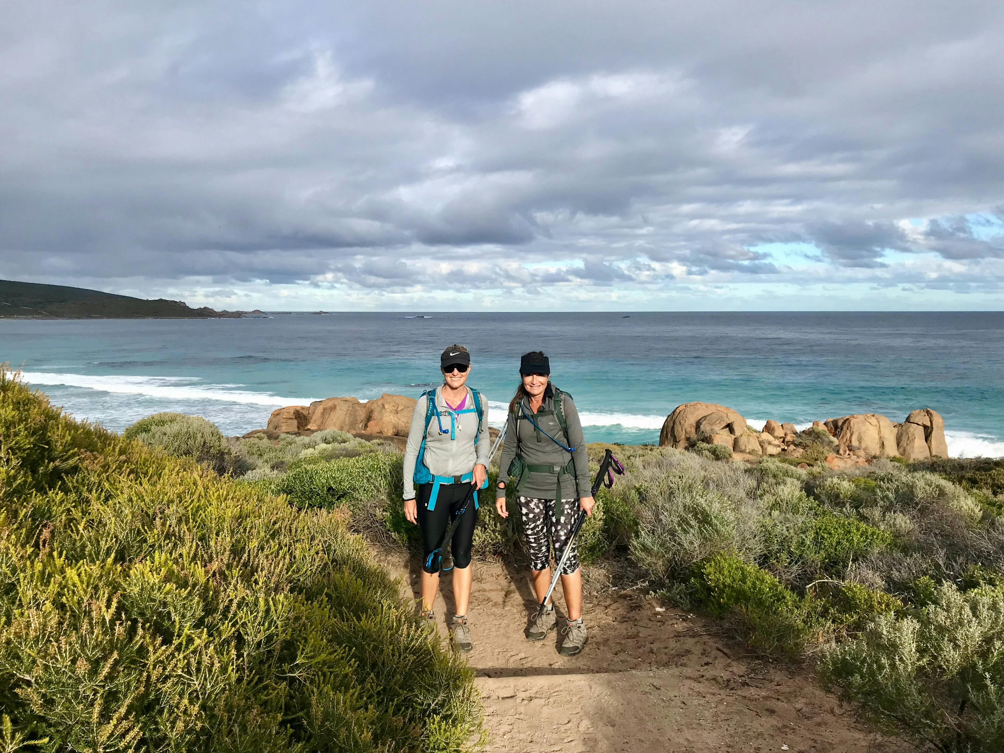 Two female hikers standing side by side on coastal path