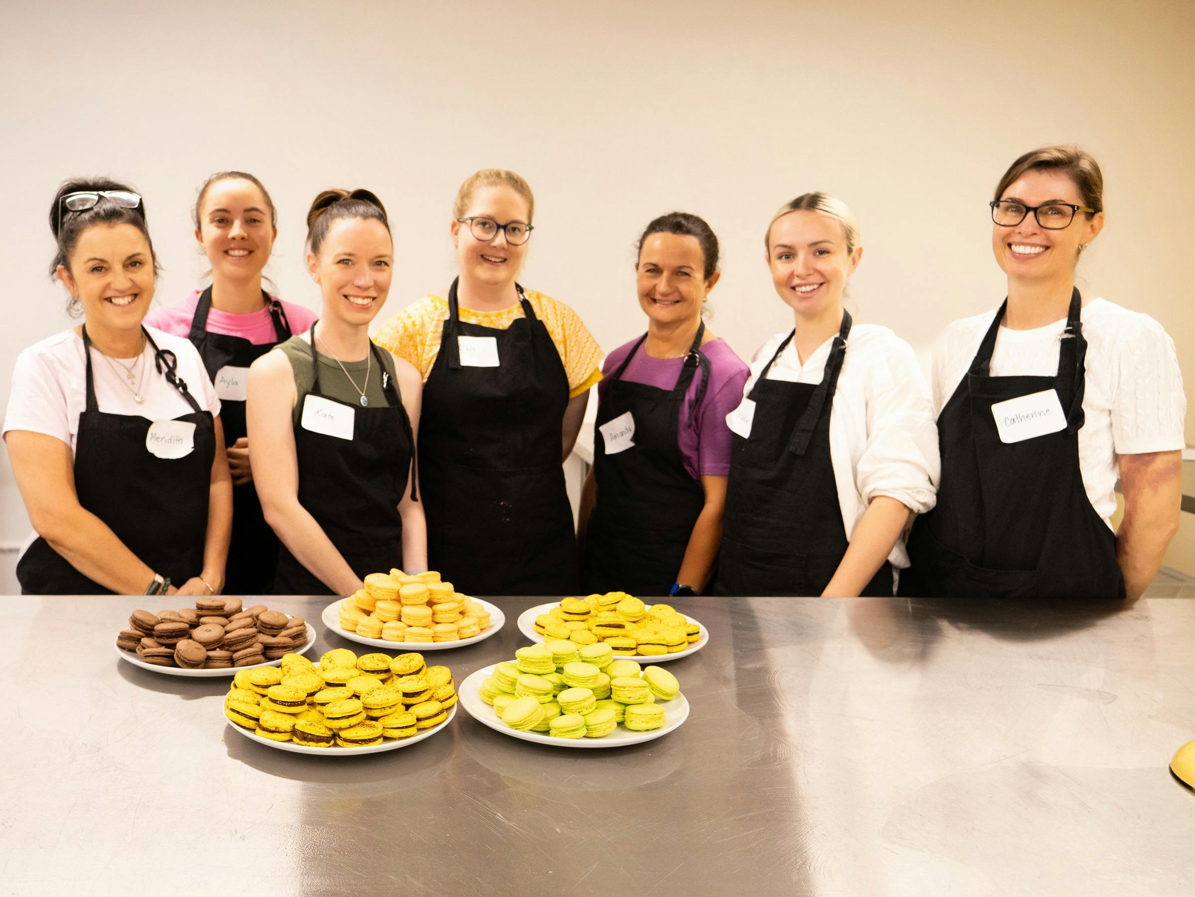 Group of people in a kitchen looking at the platters of French Macarons they have made