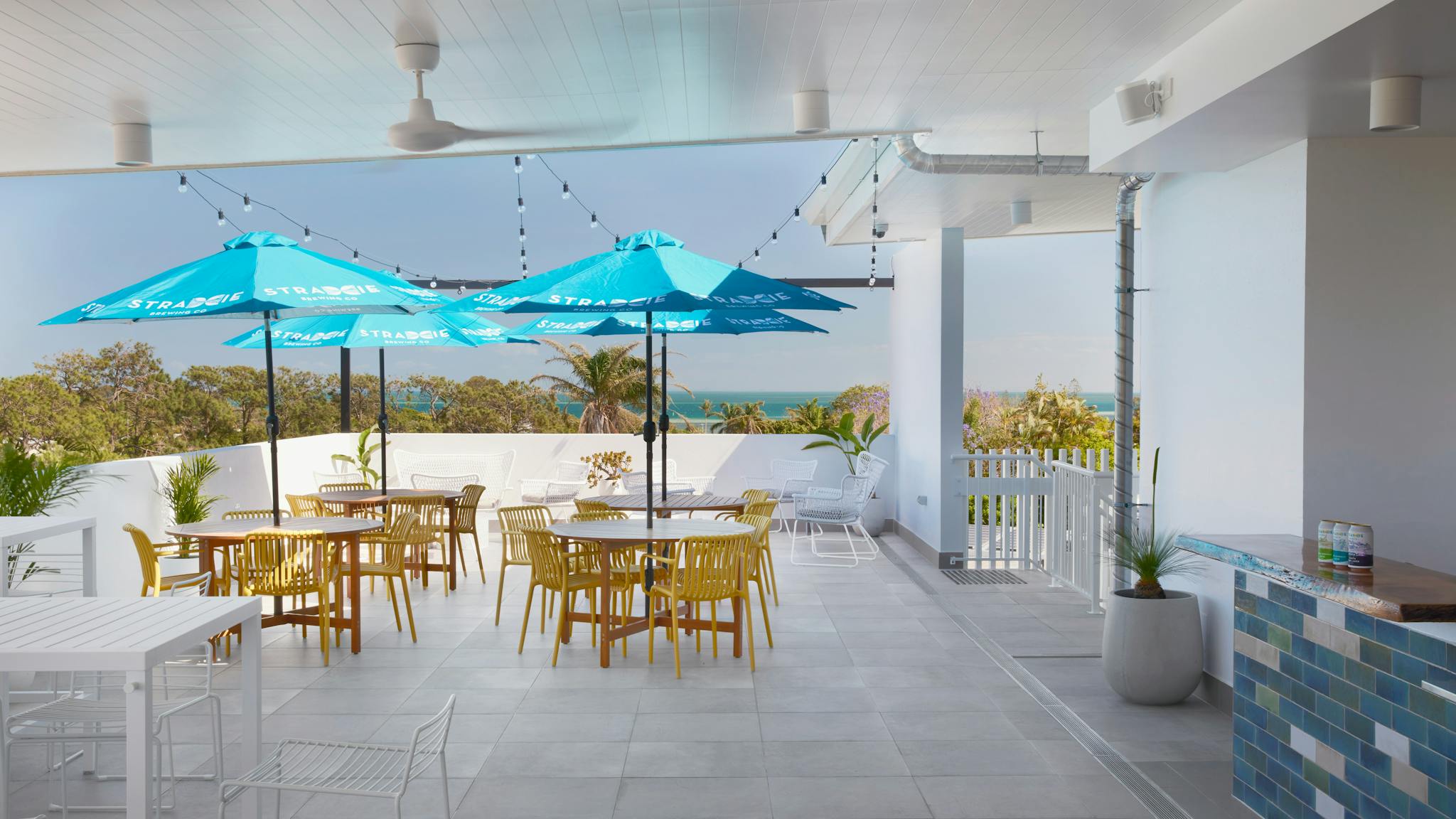 Rooftop Deck with low set tables covered with umbrellas, and views of the water and greenery