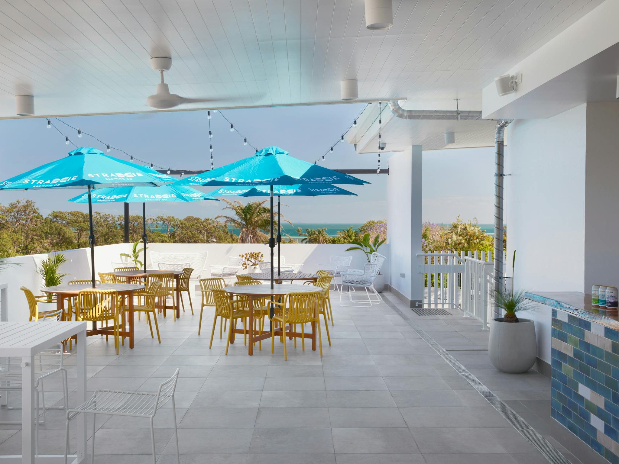 Rooftop Deck with low set tables covered with umbrellas, and views of the water and greenery Rooftop Deck with low set tables covered with umbrellas, and views of the water and greenery