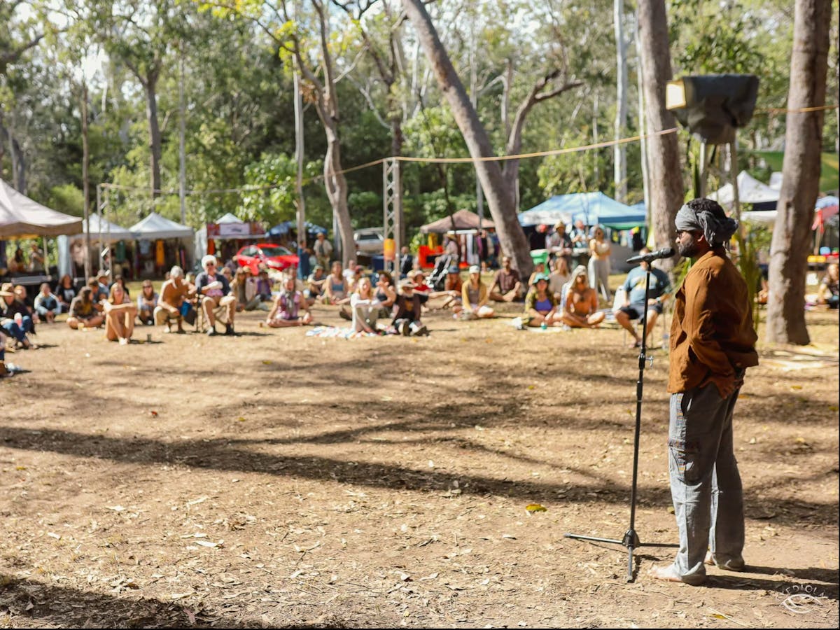 A man stands with a microphone performing at Kuranda Roots Festival in Emerald Creek, Mareeba FNQ.
