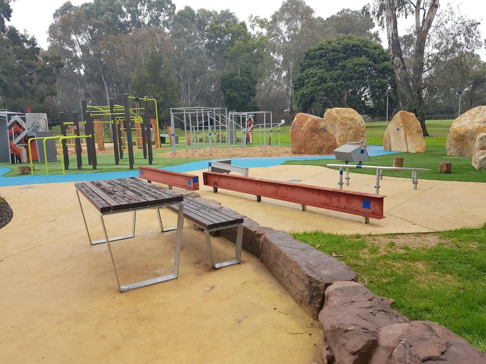 Table and seat, beam structures for climbing, rocks, path, more climbing structures, parkland, trees