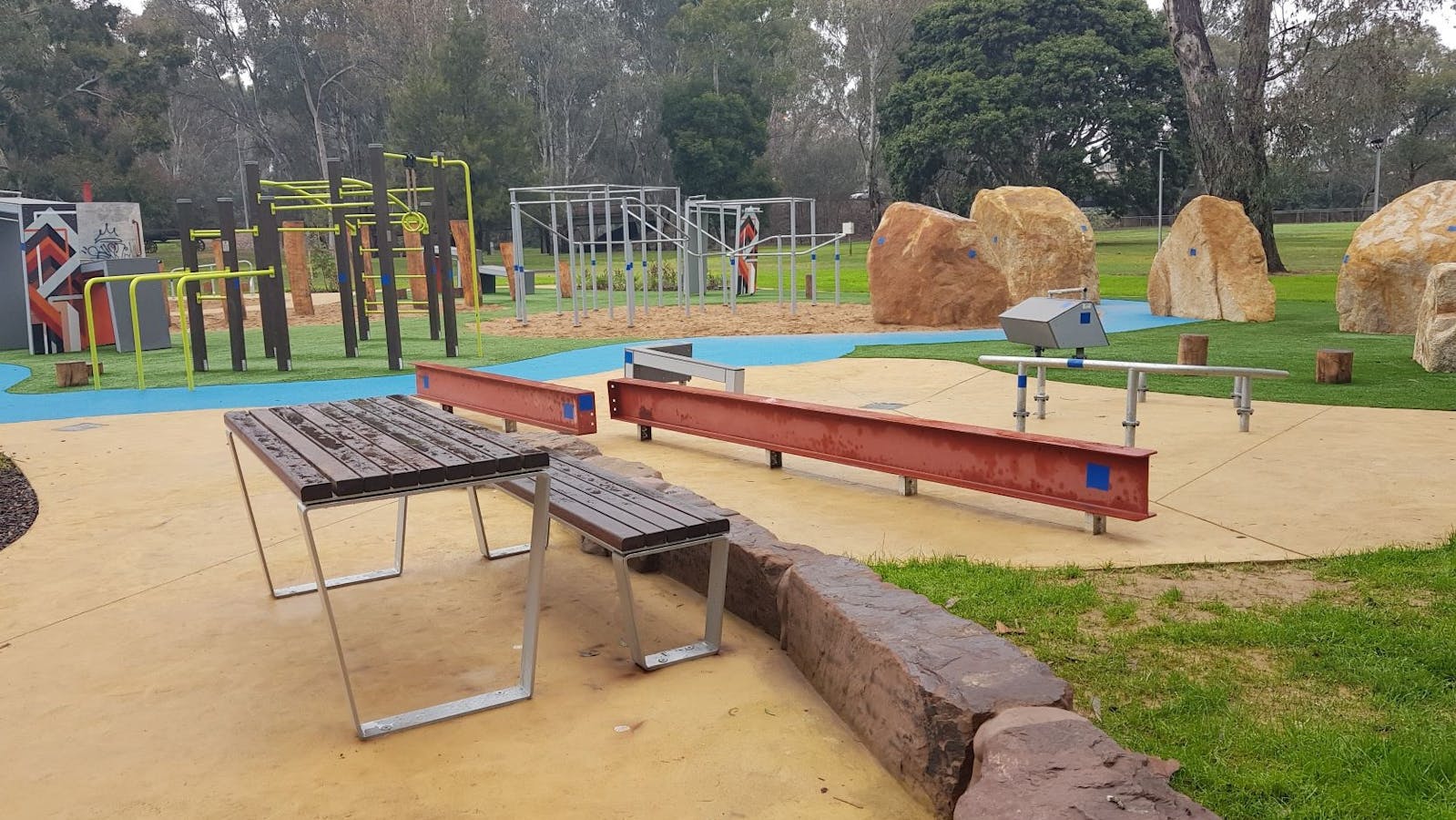Table and seat, beam structures for climbing, rocks, path, more climbing structures, parkland, trees