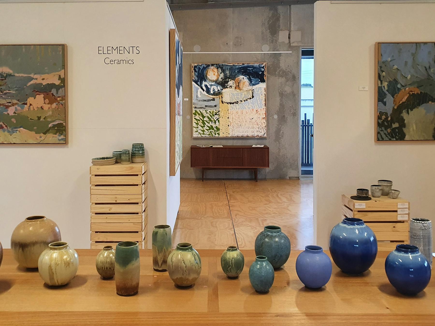 image of many coloured ceramic vessels and paintings upstairs in gallery