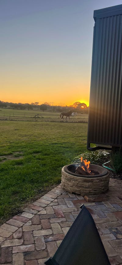 paved patio area with firepit and horses in background