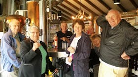 Six people in front of schnapps bar inside distillery